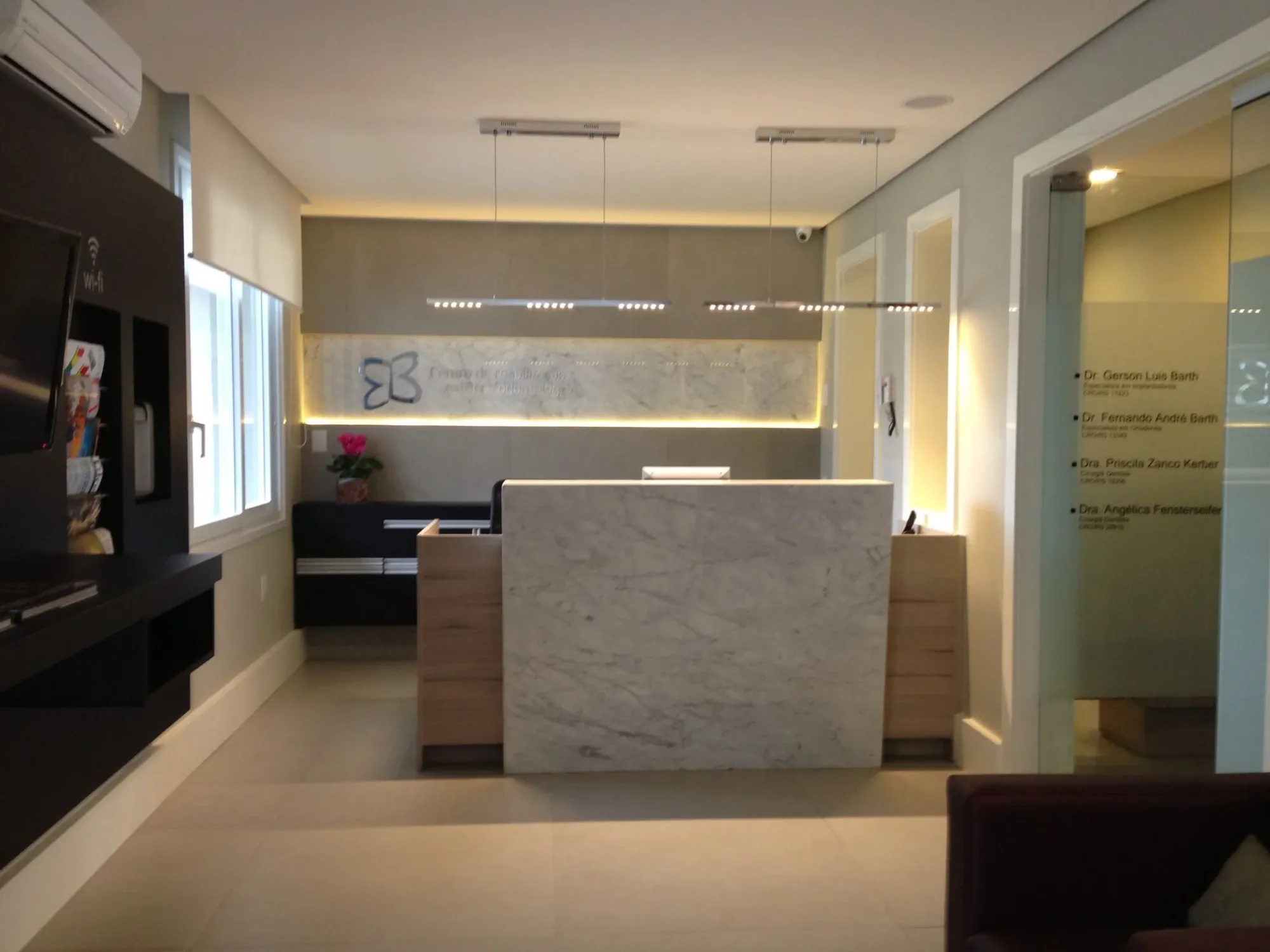 Recepção do consultório, com balcão em mármore e sala de espera